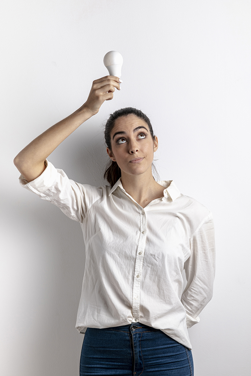 Woman holding lightbulb over her head. She is having an 'ah-ha' moment as she understands that digitalization and online portals like rentmas can solve the problems of today's construction rental companies.