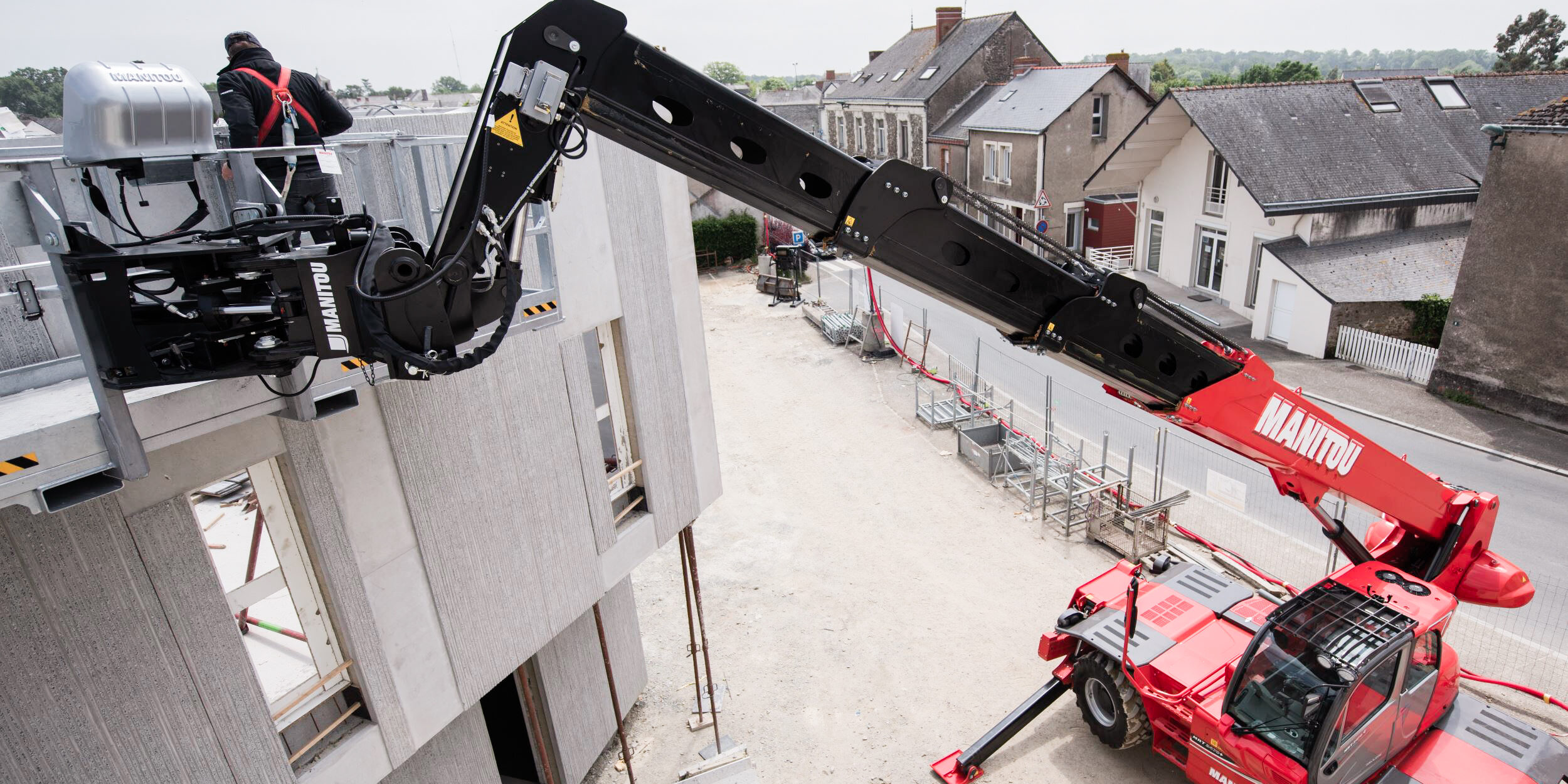 Manitou-Teleskoplader mit Mannschaufel auf einer Baustelle